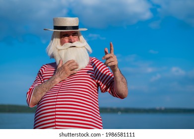 An Elderly Man In A Classic Bathing Suit Walks Along The Beach On A Hot Summer Day