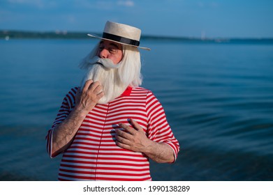 An Elderly Man In A Classic Bathing Suit Walks Along The Beach On A Hot Summer Day