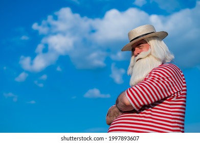 An Elderly Man In A Classic Bathing Suit Walks Along The Beach On A Hot Summer Day