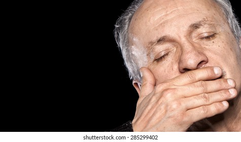 An Elderly Man With Closed Eyes Closes And Mouth Isolated On Black With Copy-space