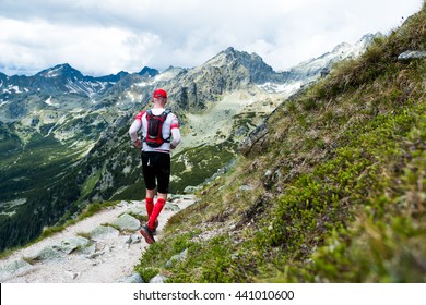 Elderly Man In Compress Socks Running Ultra Race On The Trail With Epic View On High Mountain Peaks