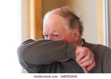 Elderly man coughing into his elbow to avoid spreading virus, germs and air born droplets amid coronavirus, Covid-19.  - Powered by Shutterstock