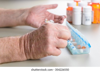 Elderly Man Counts Out His Pills And Medication For The Week Using A Daily Pill Box.