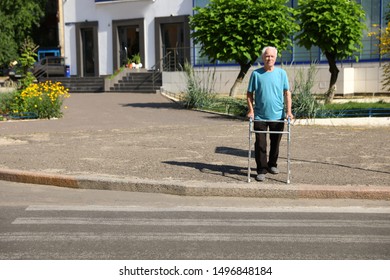 Elderly Man Crossing Street With Walking Frame. Space For Text