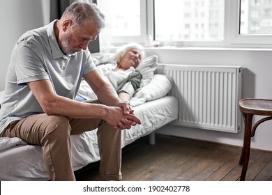 Elderly Man Crying And Mourning The Loss Of His Wife, Sitting By Her Side. Coronavirus, Covid-19 Concept