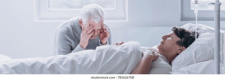 Elderly Man Crying And Mourning The Loss Of His Wife, Sitting By Her Side In The Hospital