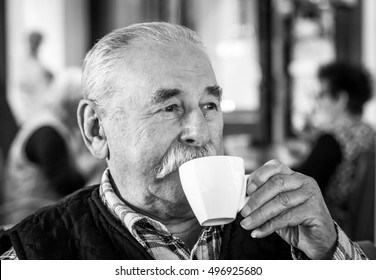 Elderly man with cup of coffee at summer cafe