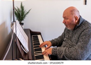 Elderly man disabled pensioner playing the piano or synthesizer. Portrait of Senior aged musician. Rehabilitation of disabled people through creativity. A person in wheelchair.
