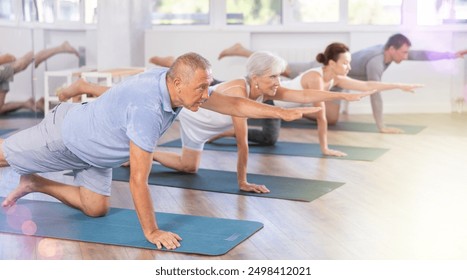 Elderly man doing pilates exercises in group in fitness studio - Powered by Shutterstock