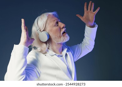 Elderly man enjoying music with headphones in stylish attire, expressing joy and freedom against a soft blue background, capturing a moment of pure bliss and relaxation