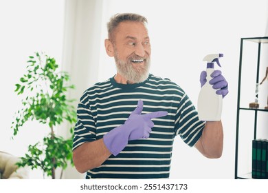 Elderly man enjoying weekend cleaning with spray bottle in sunny living room interior - Powered by Shutterstock