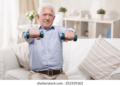 Elderly Man Exercising With Dummbells At Home