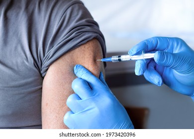 Elderly Man In Face Mask Getting Covid Vaccine. Doctor Giving Injection To Senior Man At Hospital. Virus, COVID-2019, Flu Protection. Vaccination Of Old Patient In Clinic During Coronavirus Pandemic.