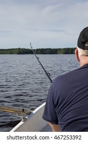 An Elderly Man Is Fishing On A Rowing Boat. He Has Just Caught A Fish And The Fishing Rod Is Bending. The Focus Point Is On The Fishing Rod.