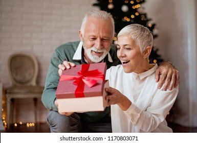 Elderly man giving a Christmas present to his wife - Powered by Shutterstock