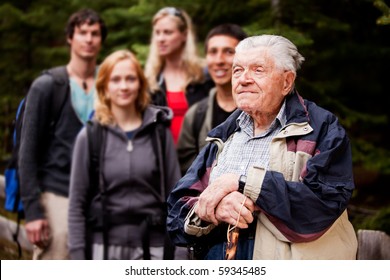 An Elderly Man Giving A Tour For A Young Group Of People