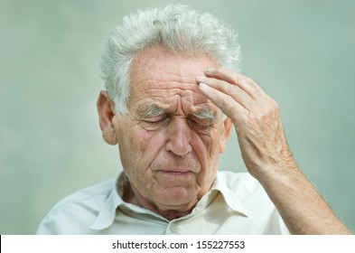 Elderly man with hand on his temple has a headache