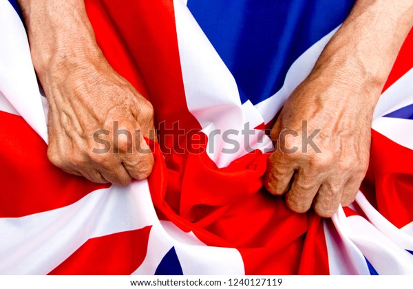 Elderly man hands holding a UK flag. The\
concept of caring for\
pensioners.
