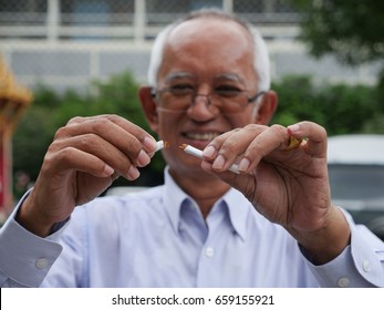 An elderly man is happy because she quit smoking. Focus on choosing cigarettes.