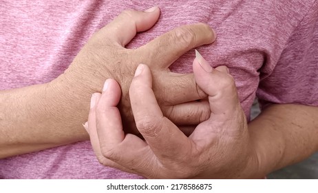 Elderly Man Holding Is Chest.