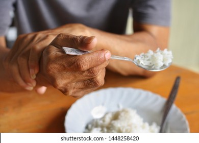 Elderly man is holding his hand while eating because Parkinson's disease.Tremor is most symptom and make a trouble for doing activities such as eat or drink.Health care or elderly concept. - Shutterstock ID 1448258420