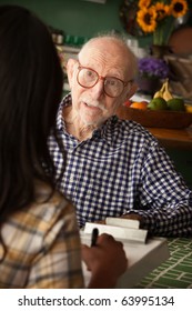 Elderly Man In Home With Care Provider Or Survey Taker In Kitchen