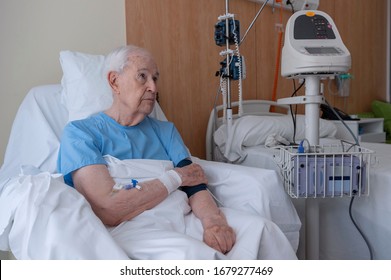 Elderly man in a hospital bed undergoing a blood pressure test
