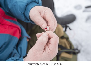 An Elderly Man Is Ice Fishing And He Is Putting A Bait On A Hook.