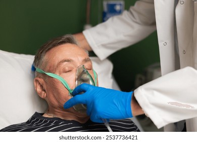 An elderly man lies in a hospital bed. A young doctor puts an oxygen mask on the patient. - Powered by Shutterstock