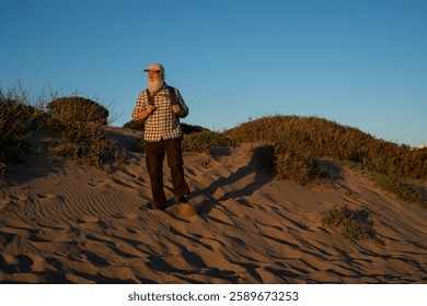 Elderly Man with a Long White Beard Hiking on Sand Dunes at Suns