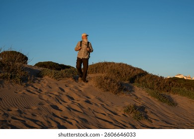 Elderly Man with a Long White Beard Hiking on Sand Dunes at Suns