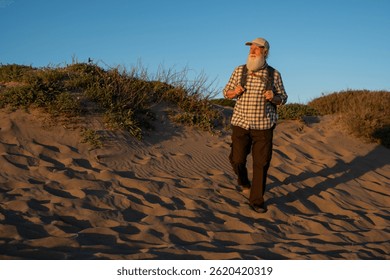 Elderly Man with a Long White Beard Hiking on Sand Dunes at Suns