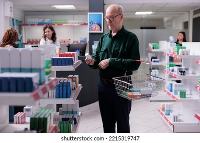 Elderly Man Looking At Pills Package During Medication Shopping In Pharmacy. Old Customer Reading Cardiology Drug Leaflet, Buying Pharmaceutical Treatment To Cure Disease. Medicine Concept