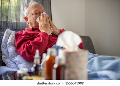 Elderly man lying on the bed and blow his nose ,  flu concept with pills and syrups - Powered by Shutterstock