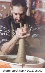 elderly man making pot using pottery wheel in studio