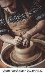 elderly man making pot using pottery wheel in studio