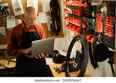 elderly man Mechanic checking data on a laptop in workshop or garage during servicing or bike repair. Copy space