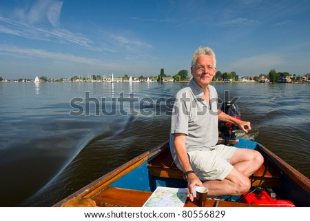 Elderly man is in motorboat at recreational water in Holland