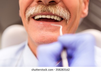 Elderly man on a review of a dentist, sitting in a chair - Powered by Shutterstock