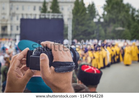 An elderly man on a video camera shoots a religious procession, an elective focus, a blurred background