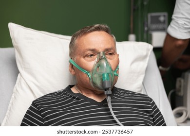 An elderly man with an oxygen mask over his face rests in a hospital bed. - Powered by Shutterstock