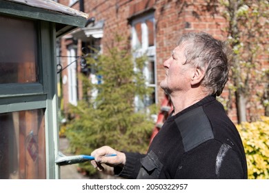 An Elderly Man Painting A Garden Shed With Preservative Paint