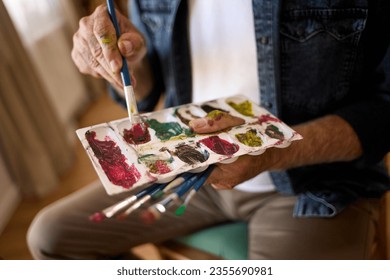 Elderly man painting on a canvas at home - Powered by Shutterstock