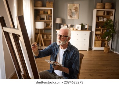 Elderly man painting on a canvas at home - Powered by Shutterstock