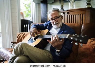 An elderly man is playing guitar