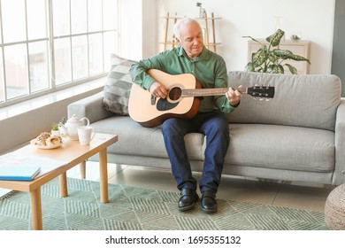 Elderly man playing guitar at home - Powered by Shutterstock