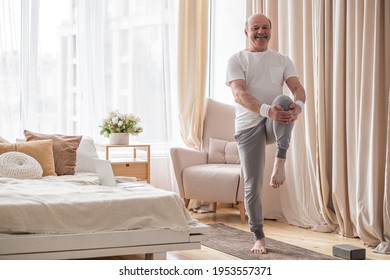 Elderly Man Practicing Yoga Or Fitness Standing On Tree Pose At Home.