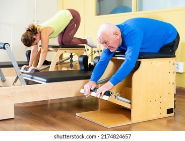 Elderly Man Press Exercises On Pilates Reformer At Studio. Front View