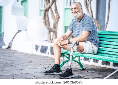 Elderly man with prosthetic leg
 left rests sitting on a park bench. Spending a relaxing afternoon. People concept. Senior mature male with amputee leg smile and enjoy relax outdoor leisure at park - Powered by Shutterstock