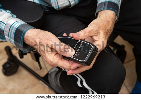 An elderly man pusching a black remote control of a electric weelchair while taking occupational therapy Stock photo © 